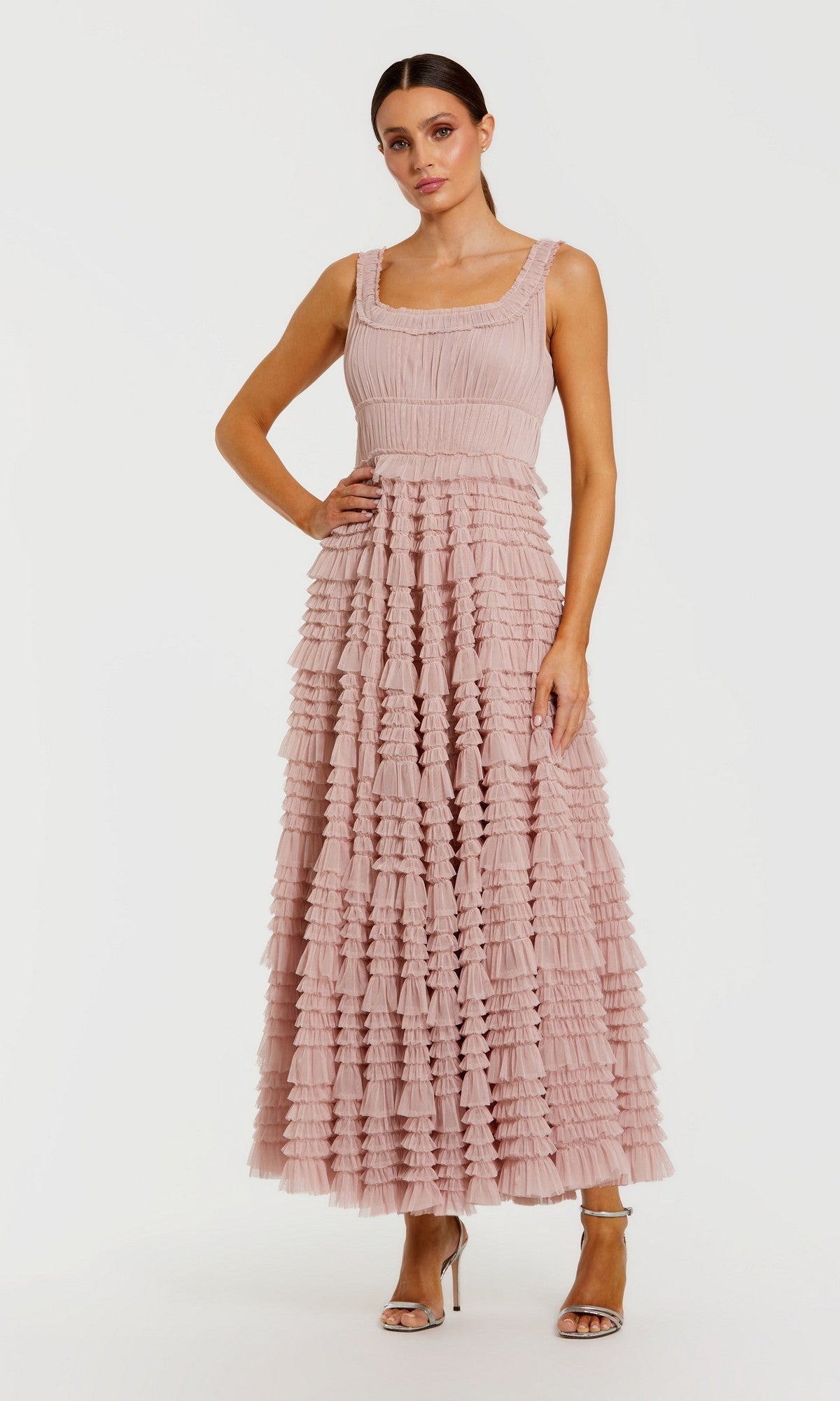 A woman stands against a plain white background wearing the Tea-Length Party Dress: Mac Duggal 8292 in rose, featuring a sleeveless design with a square neckline, layered tulle details, delicate ruffle accents, and an elegant A-line tiered skirt. She completes the look with strappy heels.